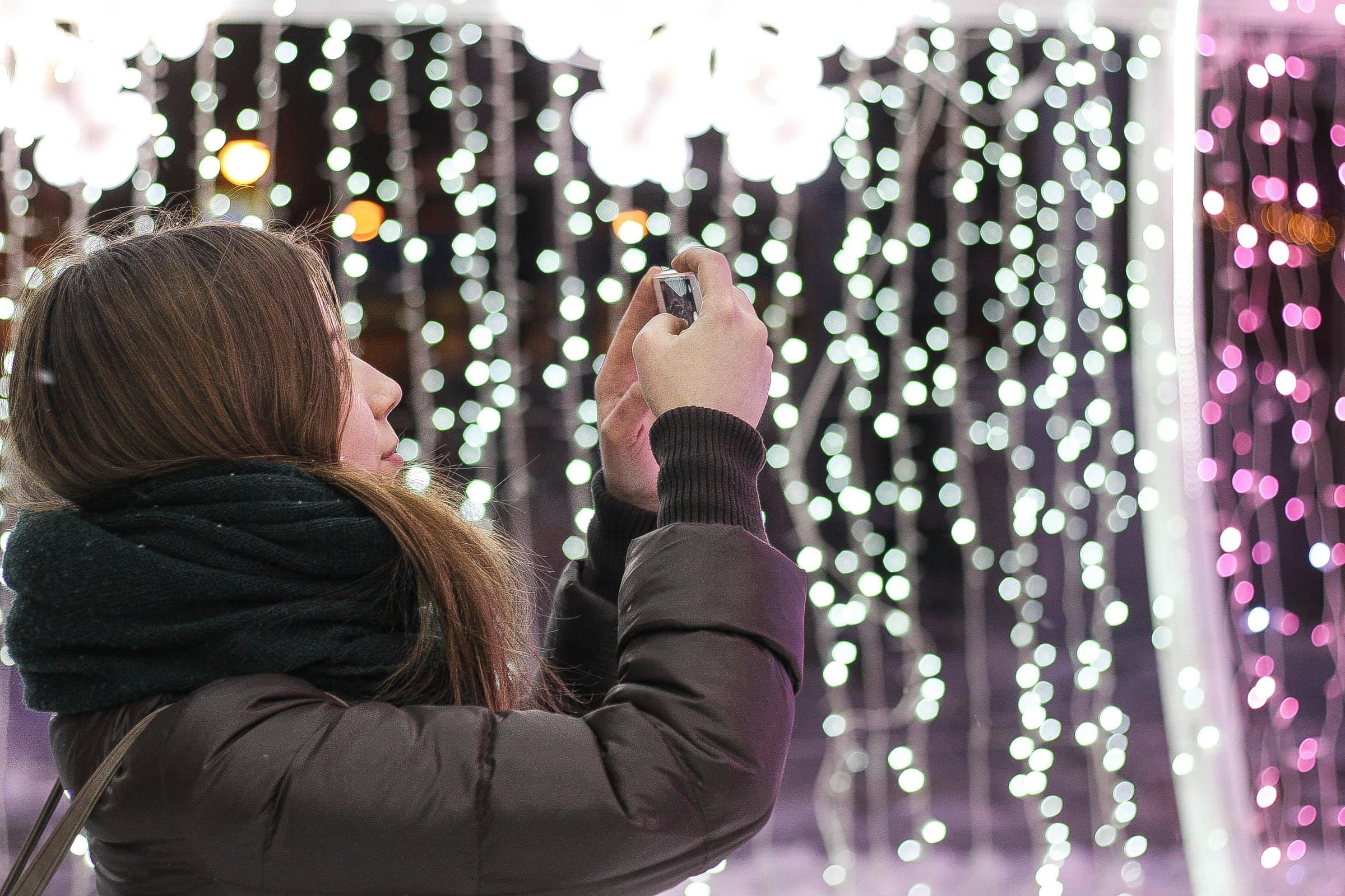 girl taking picture of holiday lights